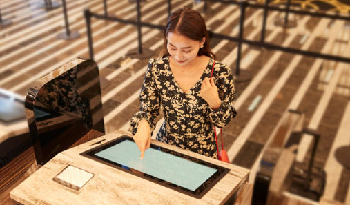 Photo: Woman operating a self-service check-in machine