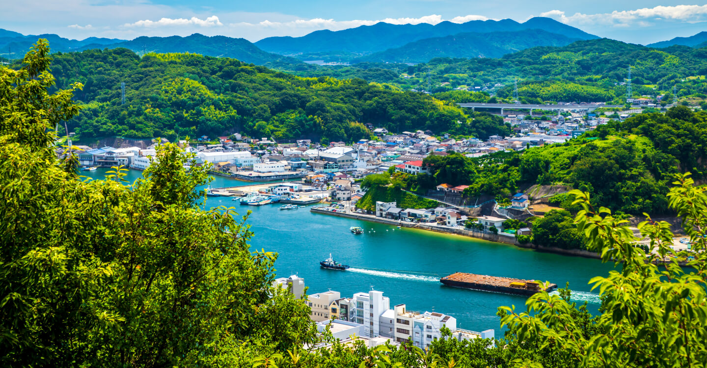 写真：広島県内の緑豊かな山に囲まれ、川が流れる町並み